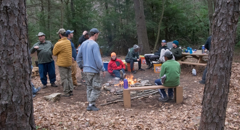 a group of veterans sit around a fire on an outward bound veterans expedition 